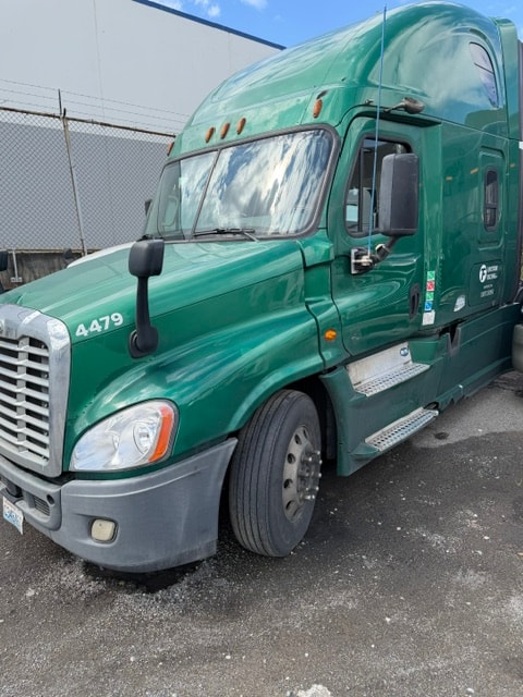 Flintstone Trucking green semi-truck in an industrial yard
