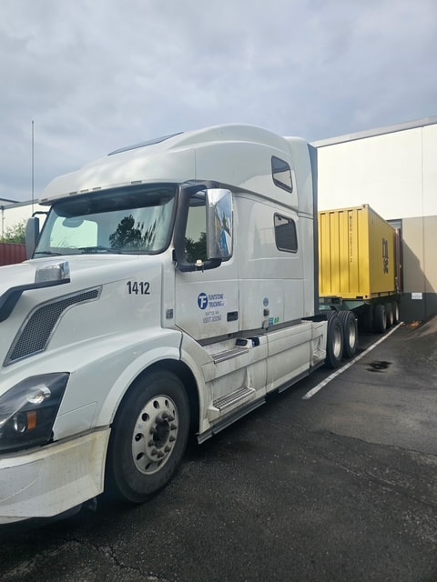 Flintstone Trucking semi-truck hauling a yellow shipping container